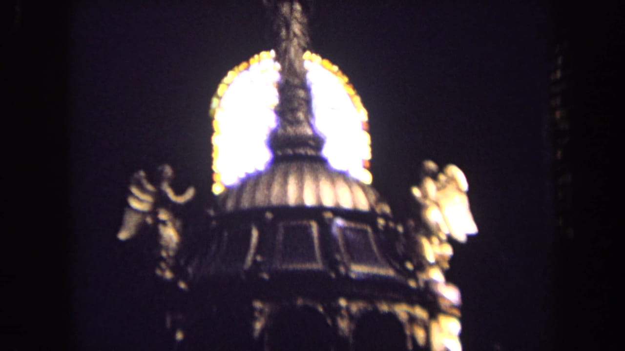 1963 England church interior frame showing a close, soft-focus view of angel statues and an ornate canopy before stained glass.