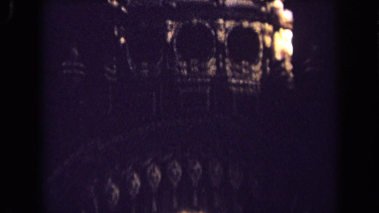 Shadowed 1963 England church interior frame with faint carved arches and ornamental wall detail visible in low light.