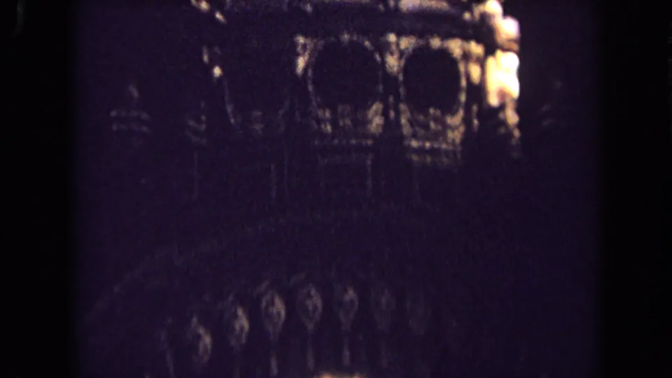 Shadowed 1963 England church interior frame with faint carved arches and ornamental wall detail visible in low light.