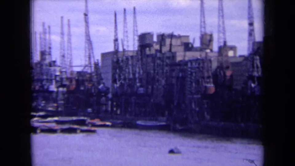 1963 England frame of dockside cranes and industrial buildings lining the river, with small craft near the waterfront.
