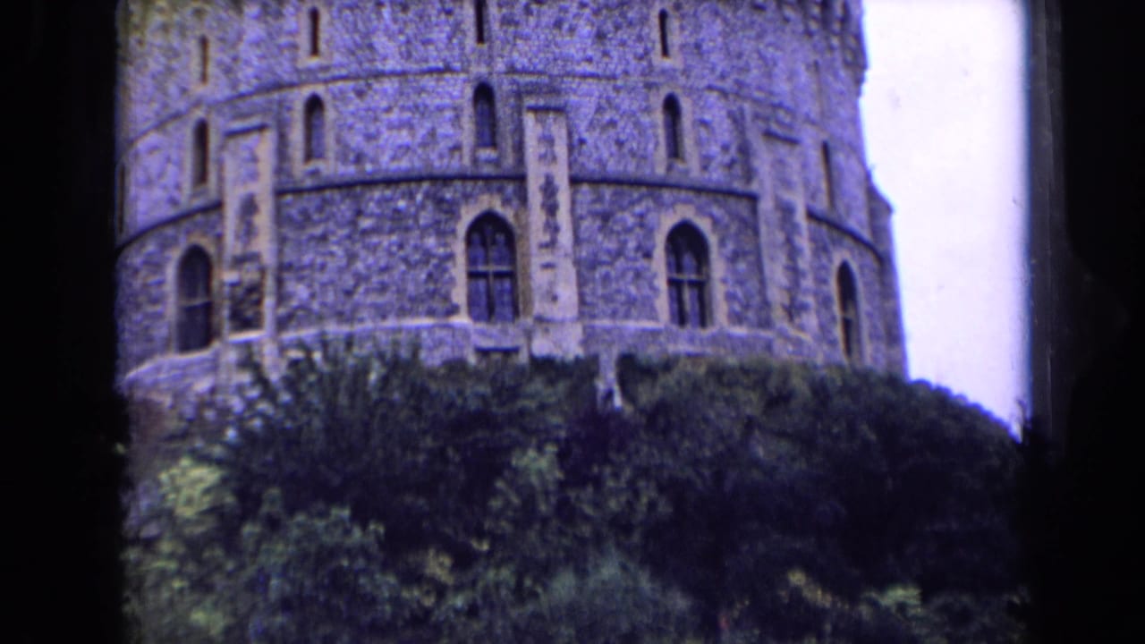 The round stone castle tower remains framed above trees, with crenellations and narrow arched windows visible.