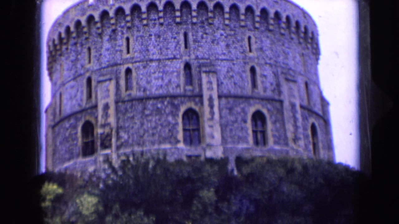 Final castle frame shows the rounded crenellated tower partly obscured by trees, with visible small-gauge film texture.