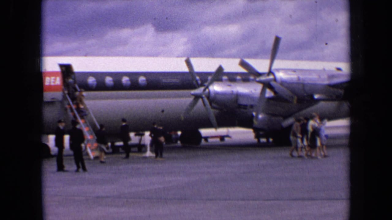 1963 England frame showing passengers crossing the airport apron beside a BEA propeller aircraft, with stairs and ground staff nearby.