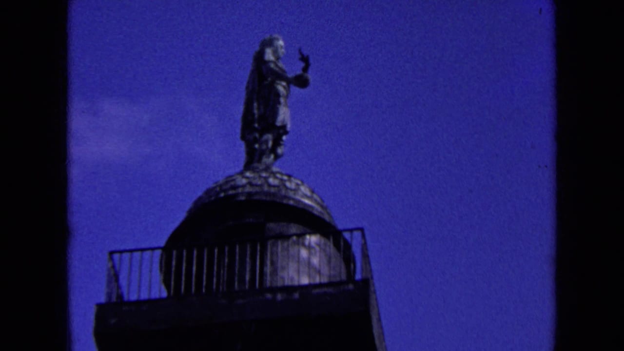 Low-angle view of a statue standing on top of a column against blue sky.