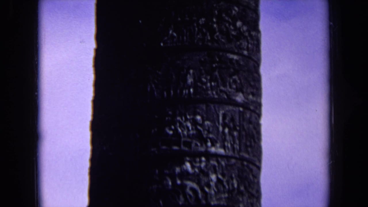 Dark carved column centered beside a vertical dark edge and pale sky.