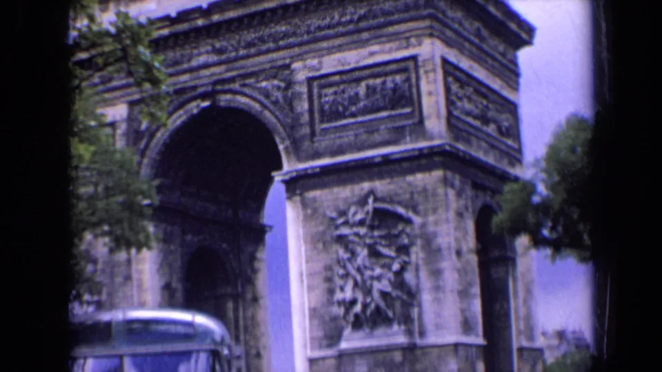 A wider 1963 travel frame shows the Arc de Triomphe, sculpted reliefs, trees, sky, and a bus partly entering the foreground.