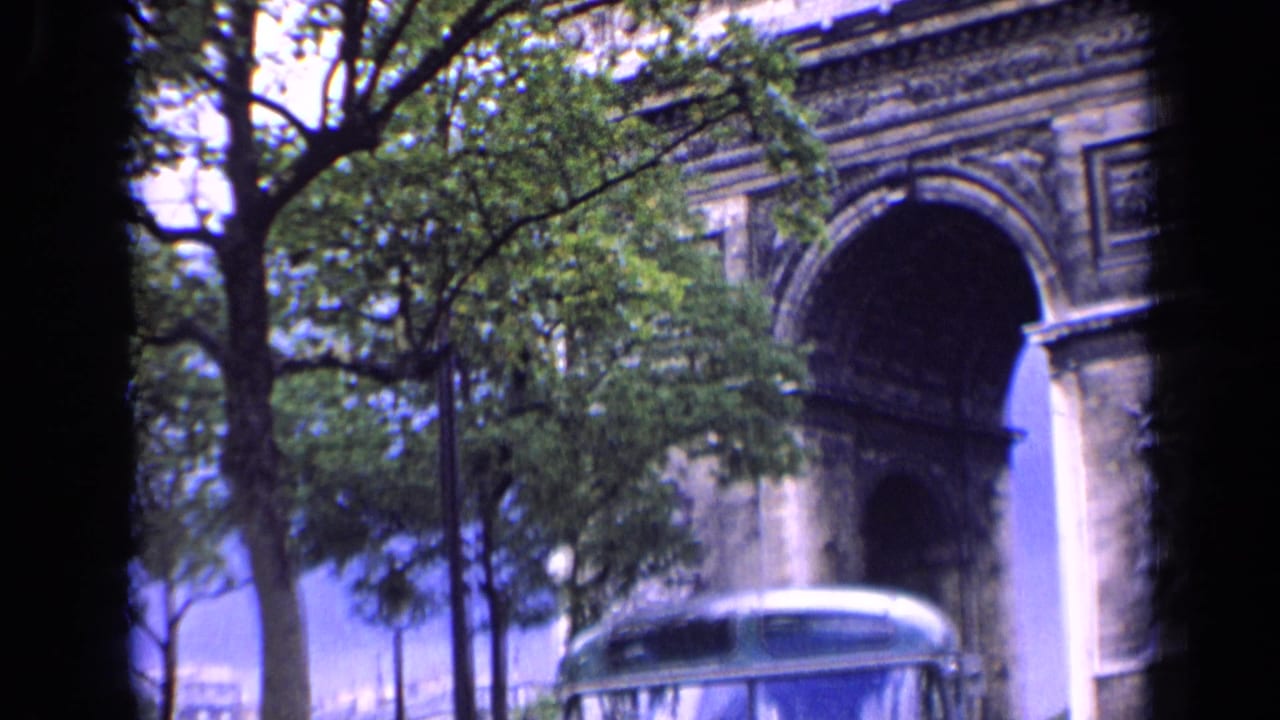 Arc de Triomphe with trees and a green-and-white bus entering the lower frame.