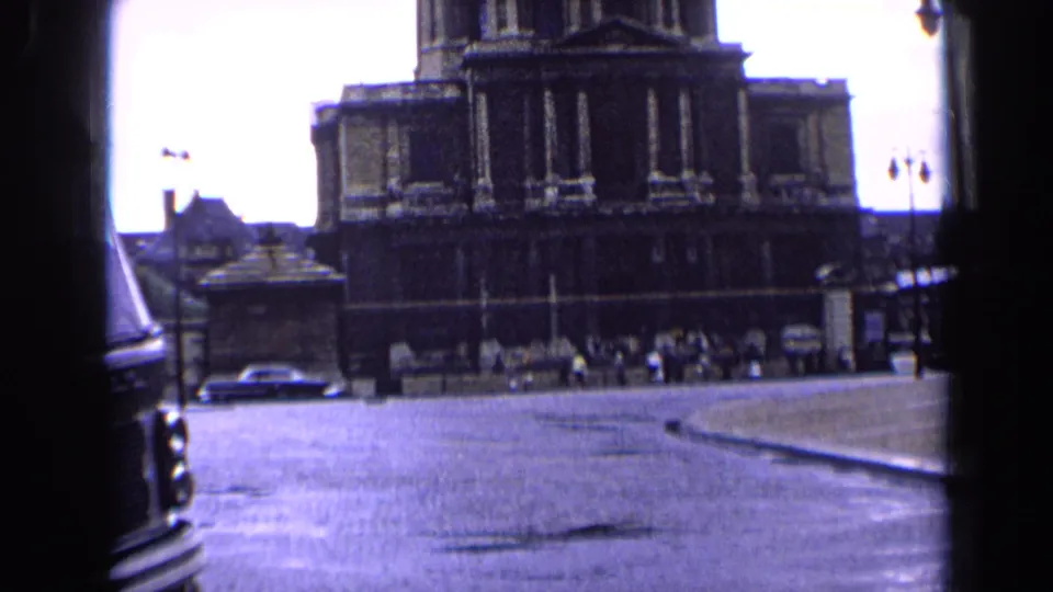 1963 Paris footage frame of a large domed public building across an open street, with cars and pedestrians in the distance.