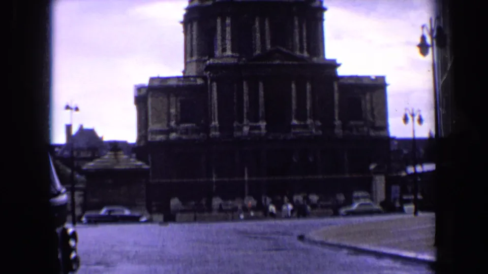 Visitor-shot 1963 Paris frame showing a domed building, street traffic, and small pedestrians through a dark window-like border.