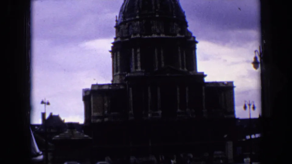 1963 Paris 8mm frame with the domed building silhouetted against a cloudy sky, bordered by dark film or window edges.