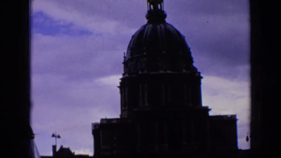 1963 France home-movie frame showing the domed church facade in deep shadow with the steeple partly near the top edge.