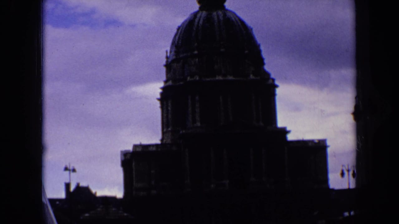 1963 8mm frame of a monumental French building in deep silhouette beneath a purple-blue sky.