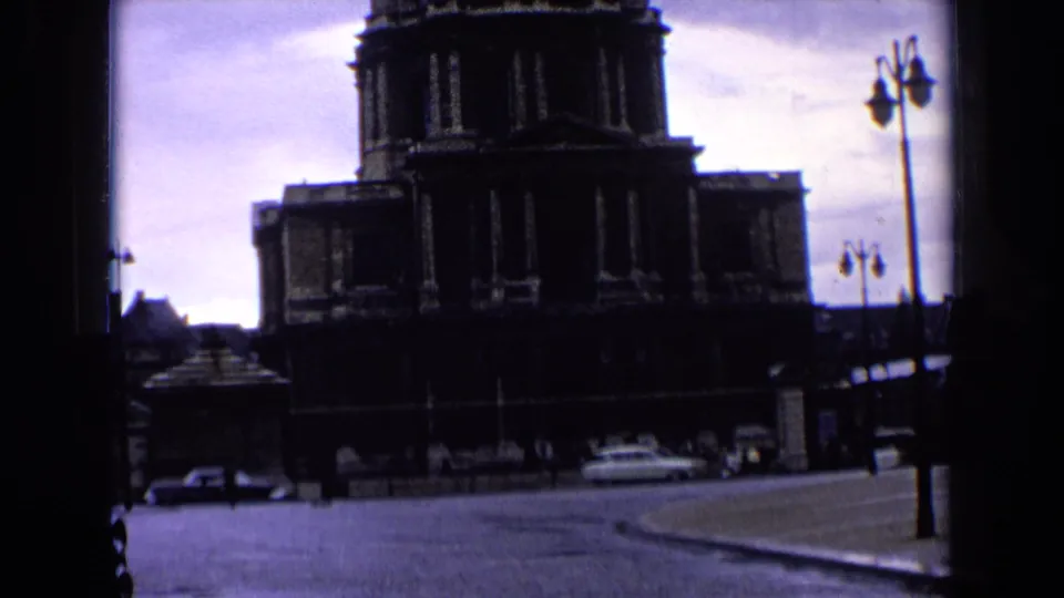 A dim 8mm view shows the monumental building over an open street with period cars and lamp posts.