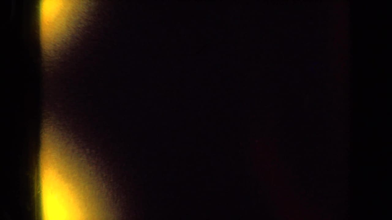 Dark film edge and warm yellow flare beside a partly visible farm silo.