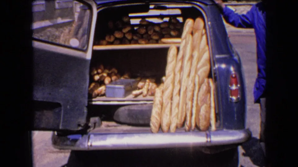 A close home-movie view shows the car's rear compartment packed with baguettes and round loaves on shelves.