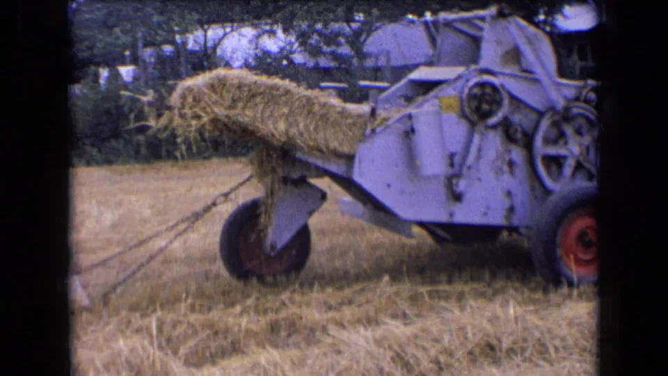 1963 France 8mm frame of a hay bale protruding from the baler chute, with the machine partly cropped at the right edge.