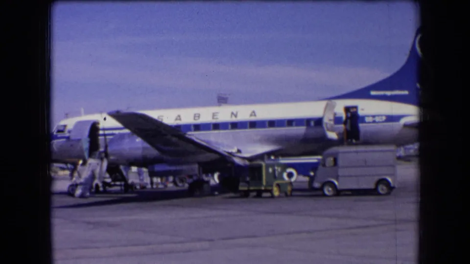 1963 France frame of a Sabena plane stopped on the airport ramp while ground crew and vehicles attend to boarding or service tasks.