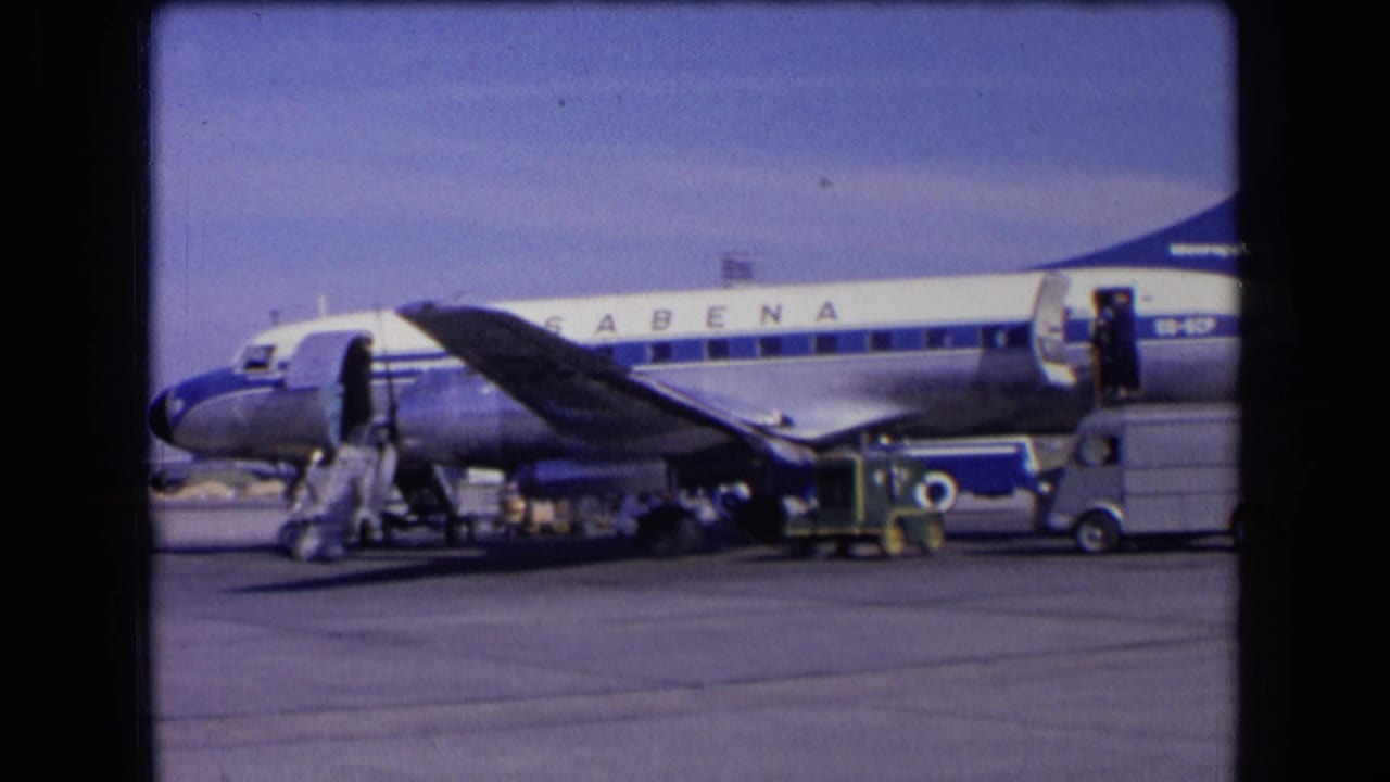 Sabena airplane on an airport tarmac with stairs, service vehicles, and people nearby.