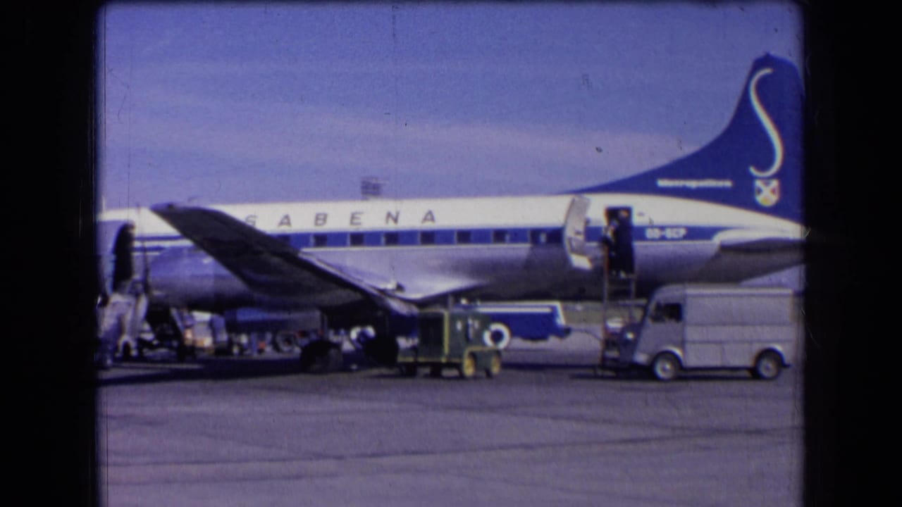 1963 France airport view of a Sabena airplane in blue and white livery with service vehicles and people beside the stairs.