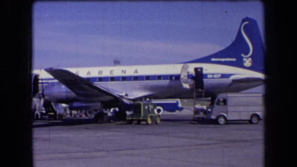 1963 France tarmac frame with Sabena tail marking, open aircraft door, passenger stairs, and nearby airport service vehicles.