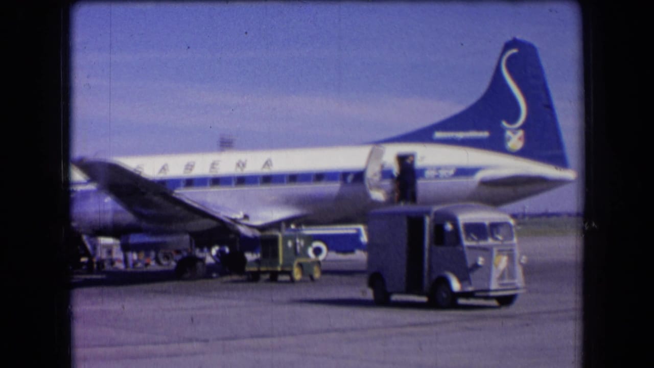 1963 France airport view of a blue-and-white Sabena jet with ground vehicles and an open aircraft door on the tarmac.