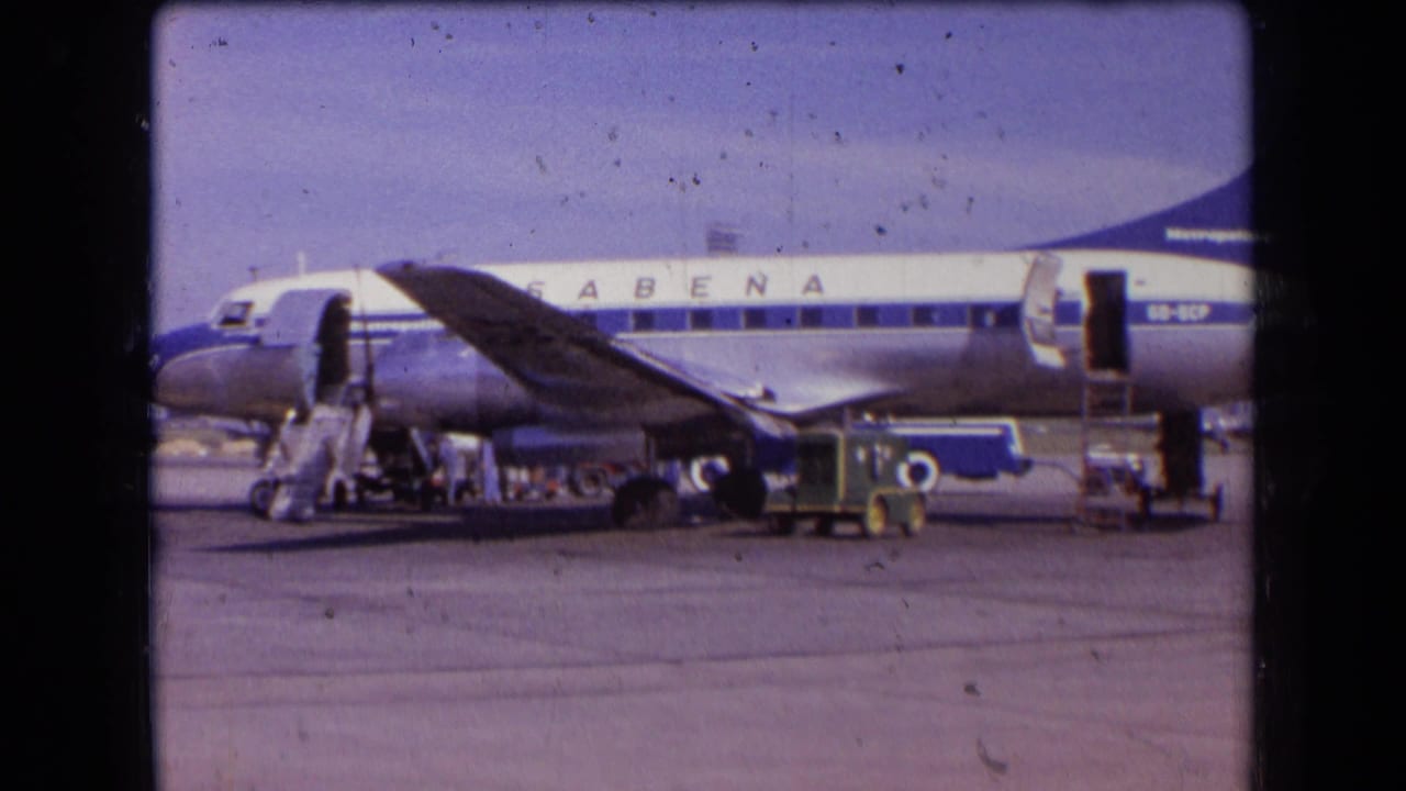 1963 France frame of a Sabena passenger plane on the apron, with open door, stairs, service vehicles, and distant workers near the fuselage.