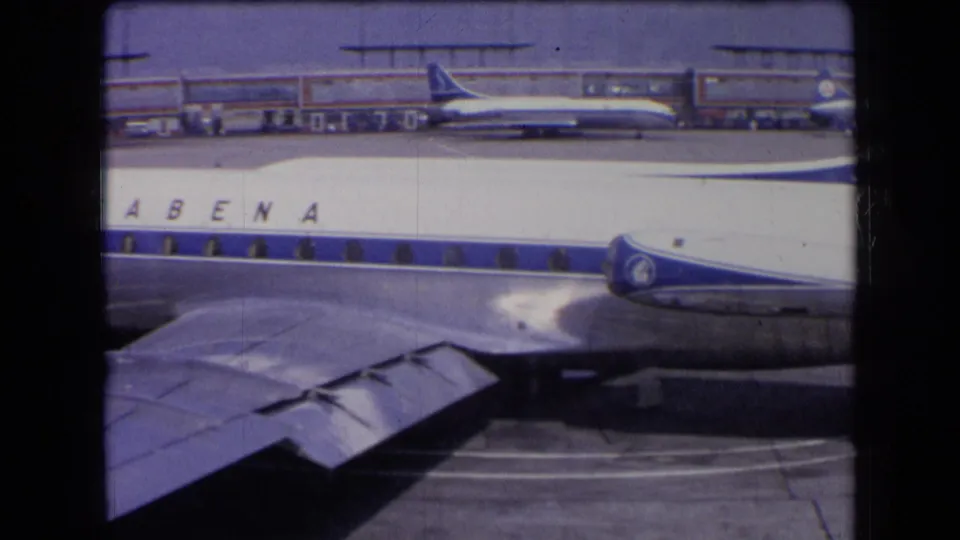 1963 France airport view of a Sabena airliner passing close to the camera, with its wing, engines, and terminal-side aircraft visible.