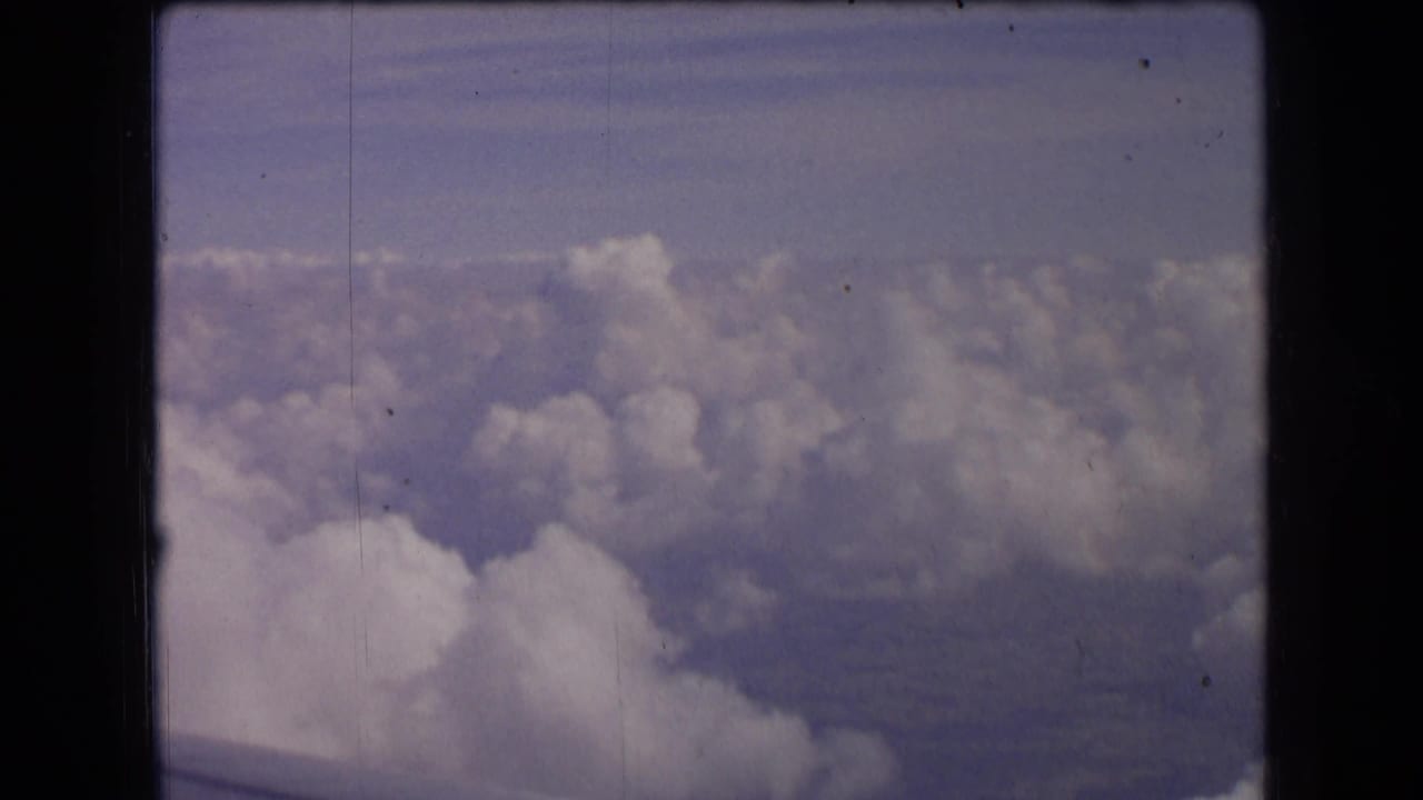 Clouds seen from above with a hazy landscape far below.