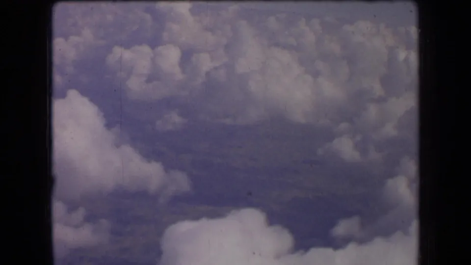 1963 France 8mm frame with soft clouds, pale sky, and distant land visible through atmospheric haze.