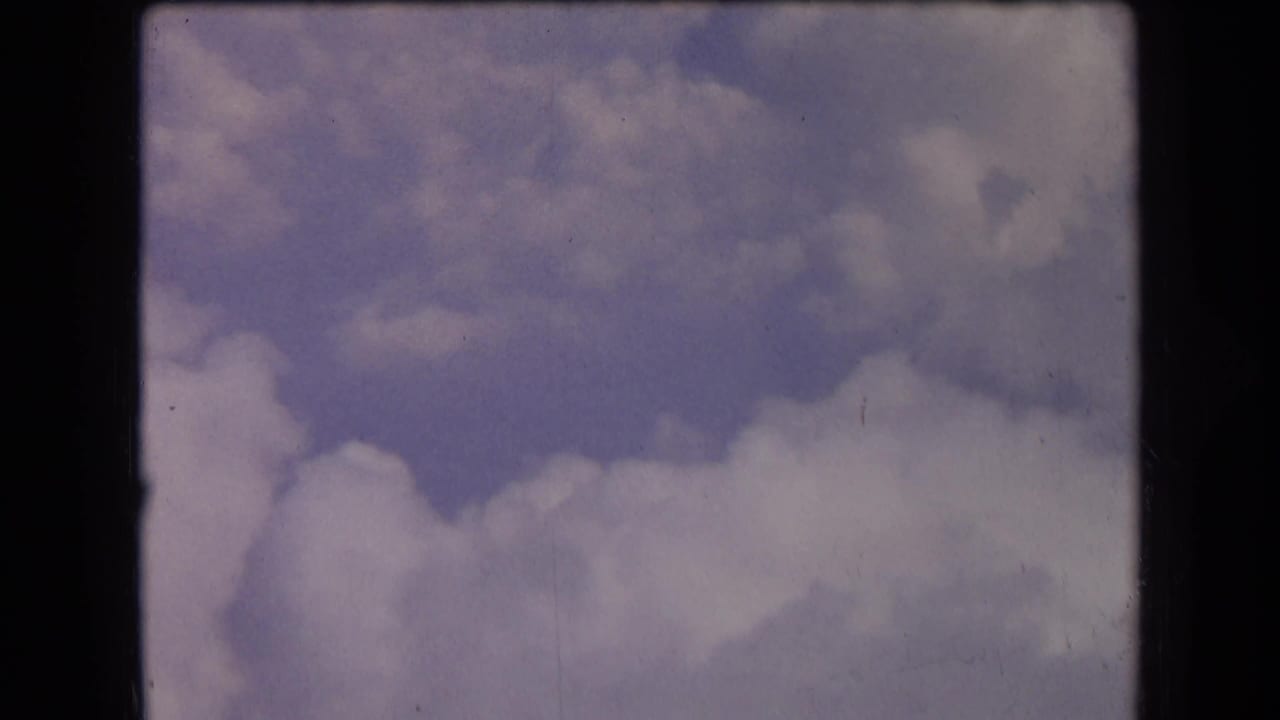 White and gray clouds against a muted blue-purple sky within dark 8mm frame edges.