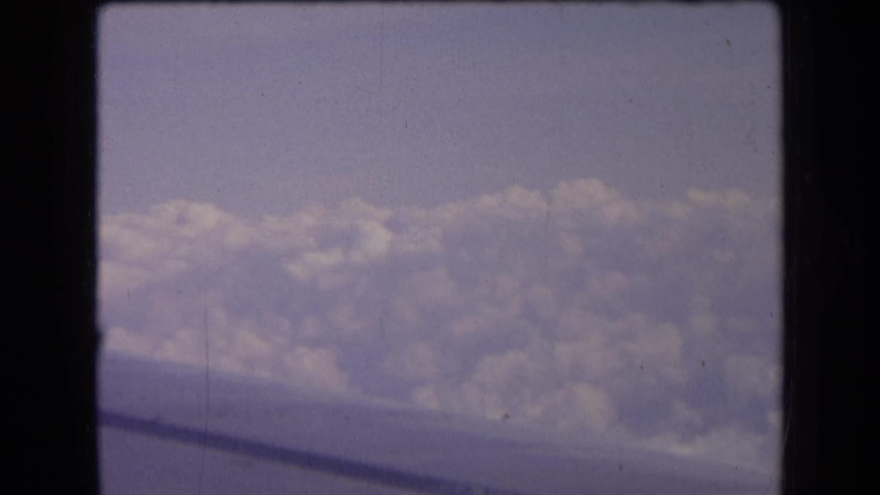 Clouds seen from an airplane window with a dark wing edge below.