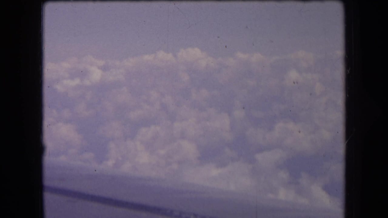 Aerial view of cloud layers with a dark wing edge along the lower frame.