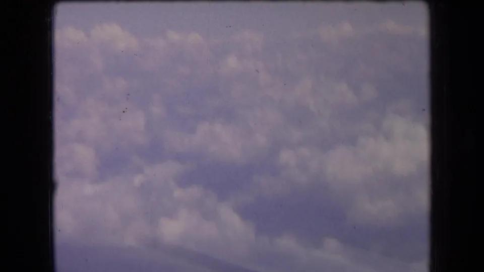 Final 1963 France 8mm frame showing a close aerial view of clouds from an aircraft window with faded color and visible film wear.