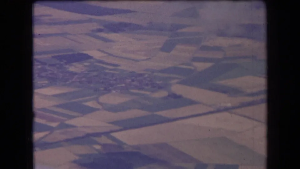 1963 France aerial home-movie frame with fields, a village edge, and visible 8mm gate borders across the contact sheet.