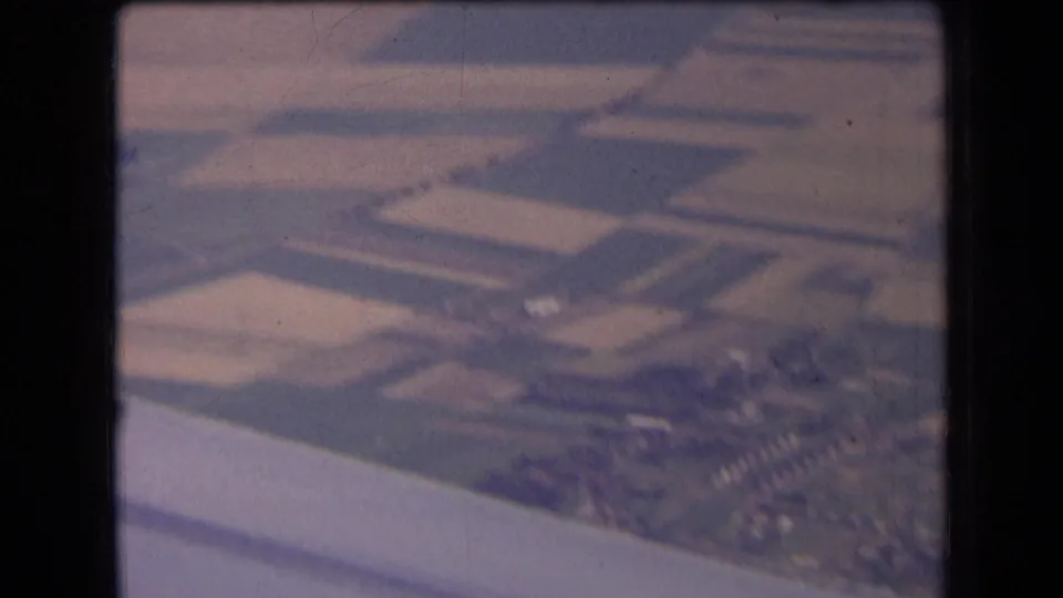 Soft 8mm aerial frame over central France, showing patchwork farmland and clustered rural buildings near the bottom edge.
