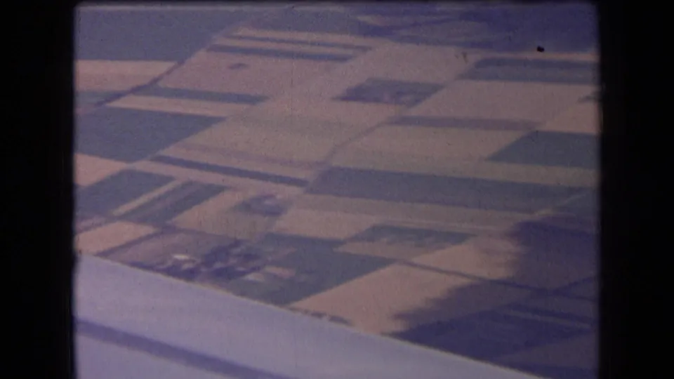 1963 France travel footage showing patchwork farmland from an airplane window, with fields in varied tones below.