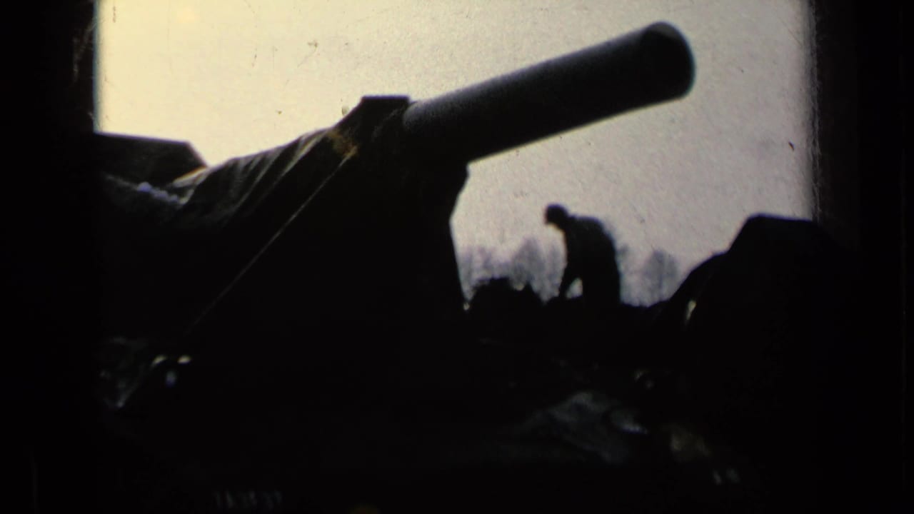 Large tank barrel with a soldier silhouetted beside covered armor.