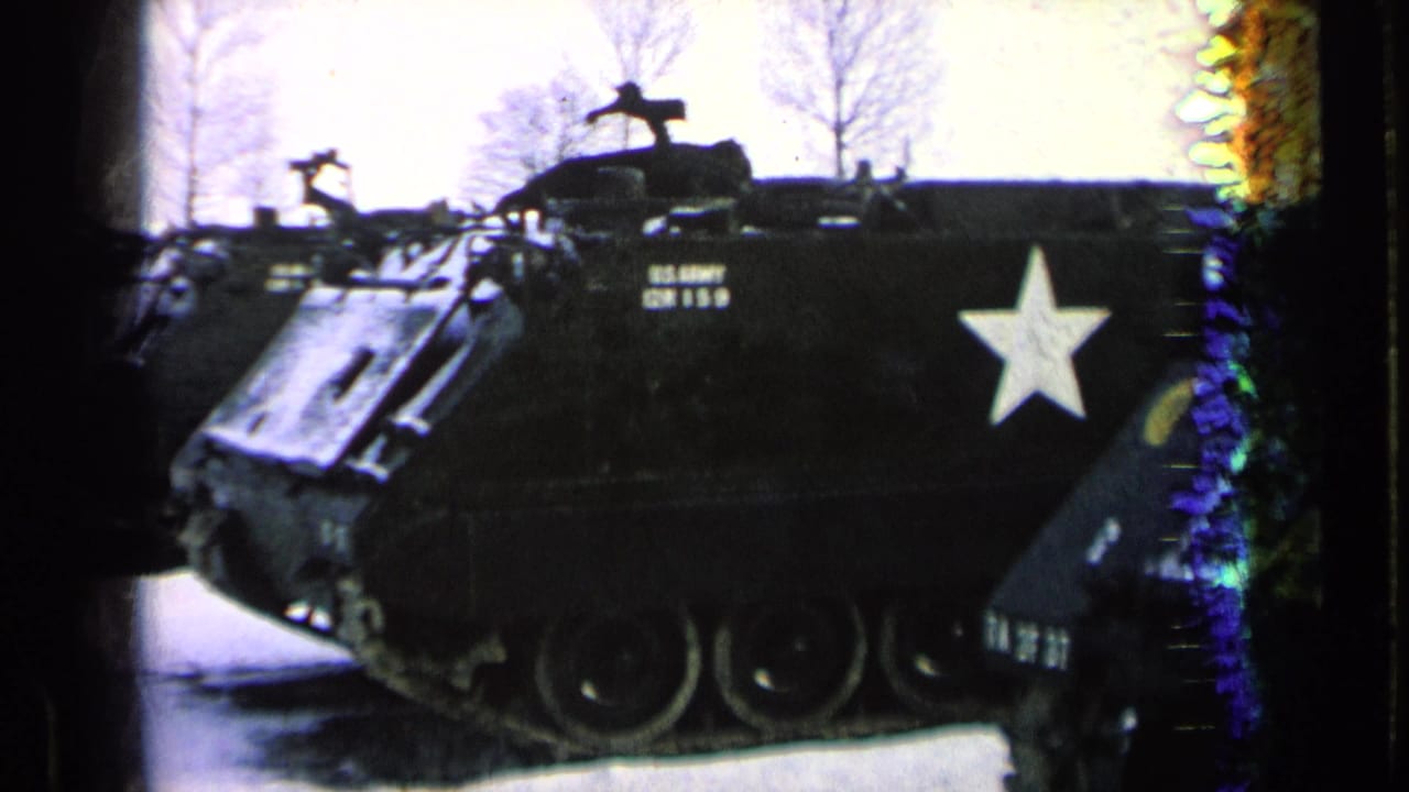 1963 8mm frame of a dark U.S. Army armored personnel carrier with a white star, seen beside bare trees in Germany.