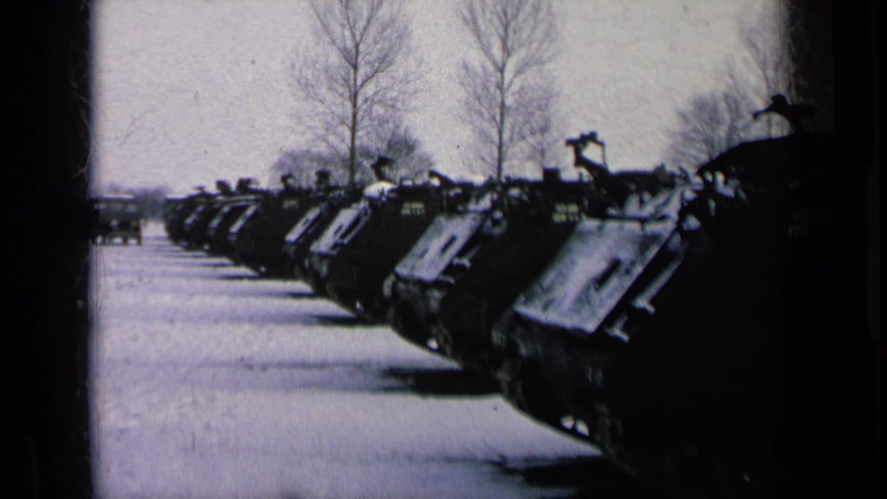 A long line of military tanks appears parked in snow at a German military base, with bare trees and a pale winter sky behind them.