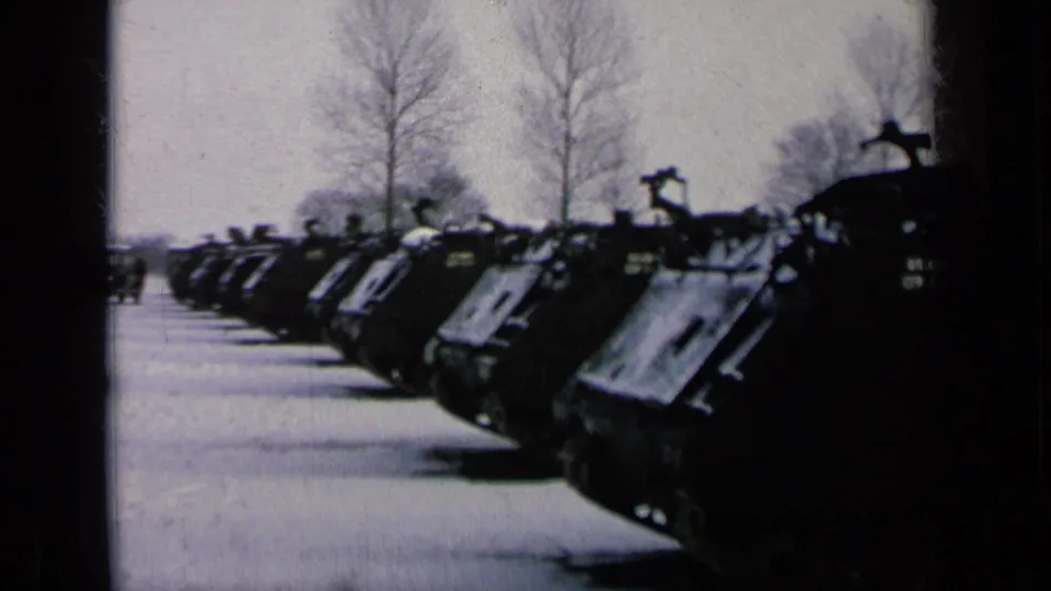 The camera frames the nearest tanks more prominently, with the parked line continuing back through the snowy base setting.