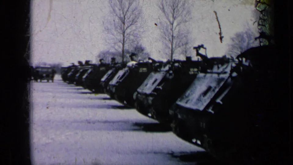 A row of tanks remains parked in the snow, framed by bare trees, dark film borders, and visible 8mm wear.
