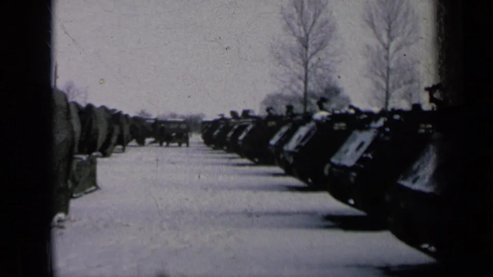 Final 8mm frame of the clip, with tanks in static winter formation across a snow-covered military lot.