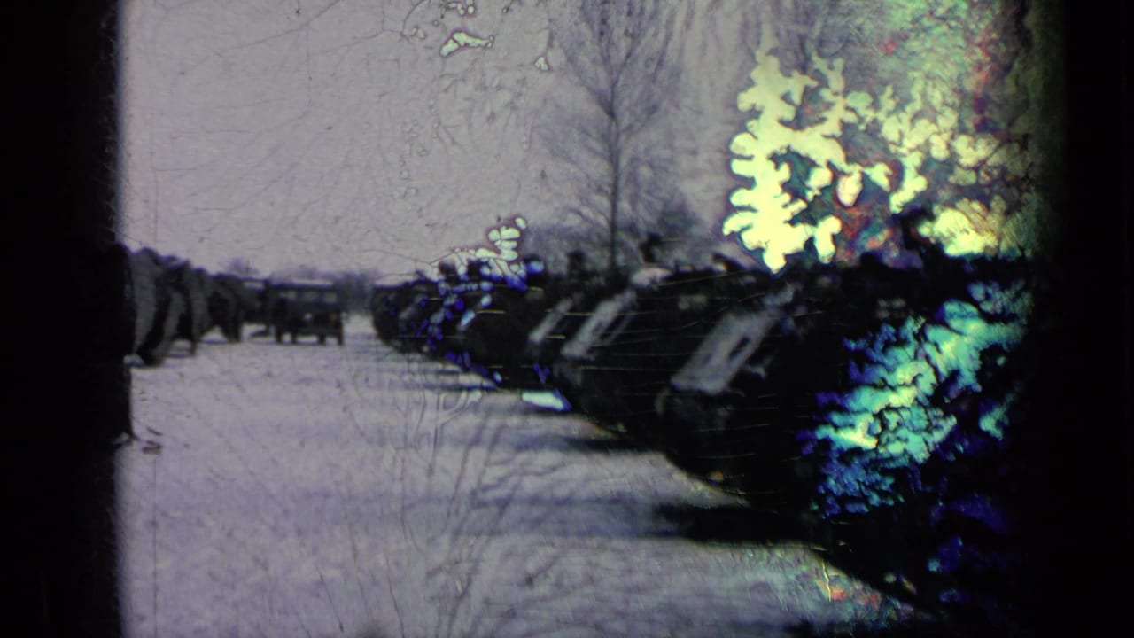 1963 8mm frame of armored vehicles lined beside a snowy base road, with a distant truck and visible light-leak damage.