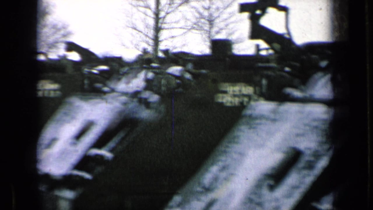 Parked U.S. Army armored vehicles lined up near bare trees.
