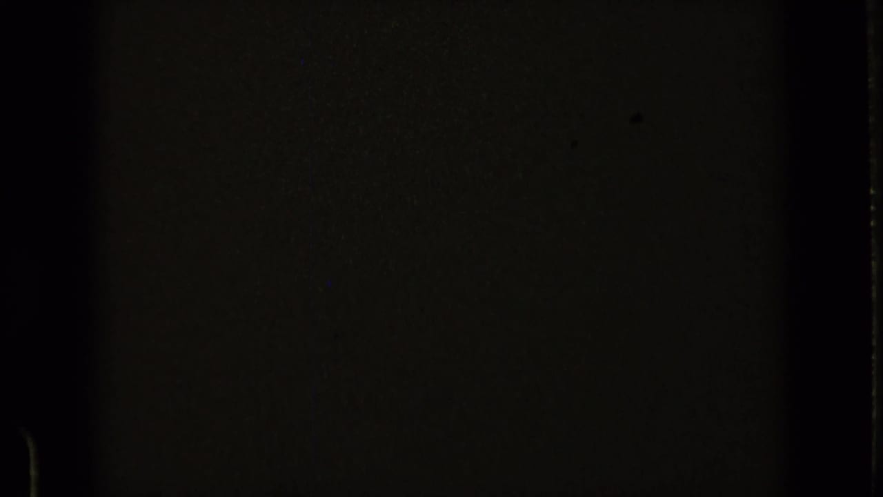 Dark, underexposed film frame with faint frame edges and grain.