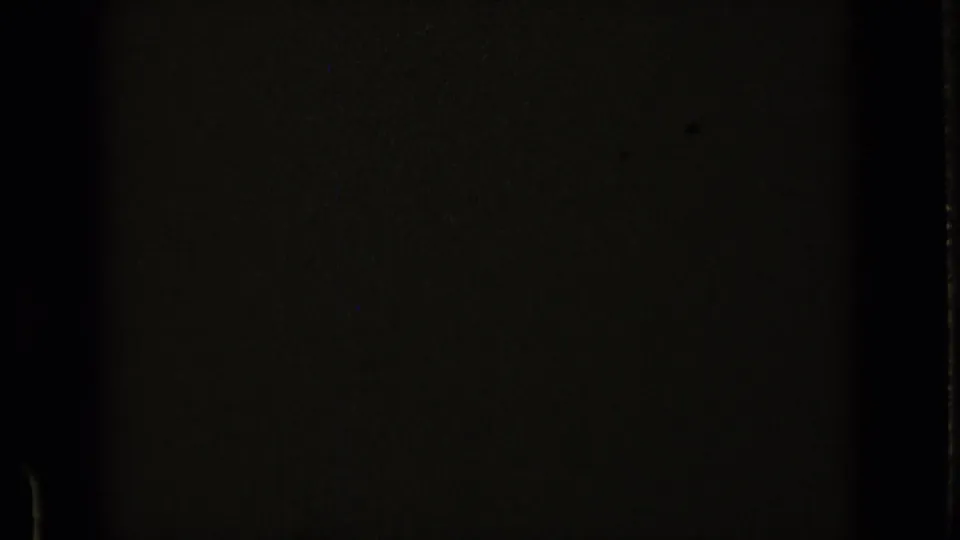 Mostly dark 8mm frame at the start of the clip, with faint borders, grain, and minimal visible scene detail.