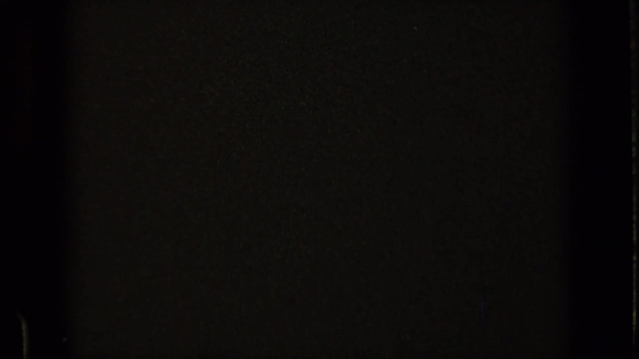 Dark film frame with faint borders and little visible detail.