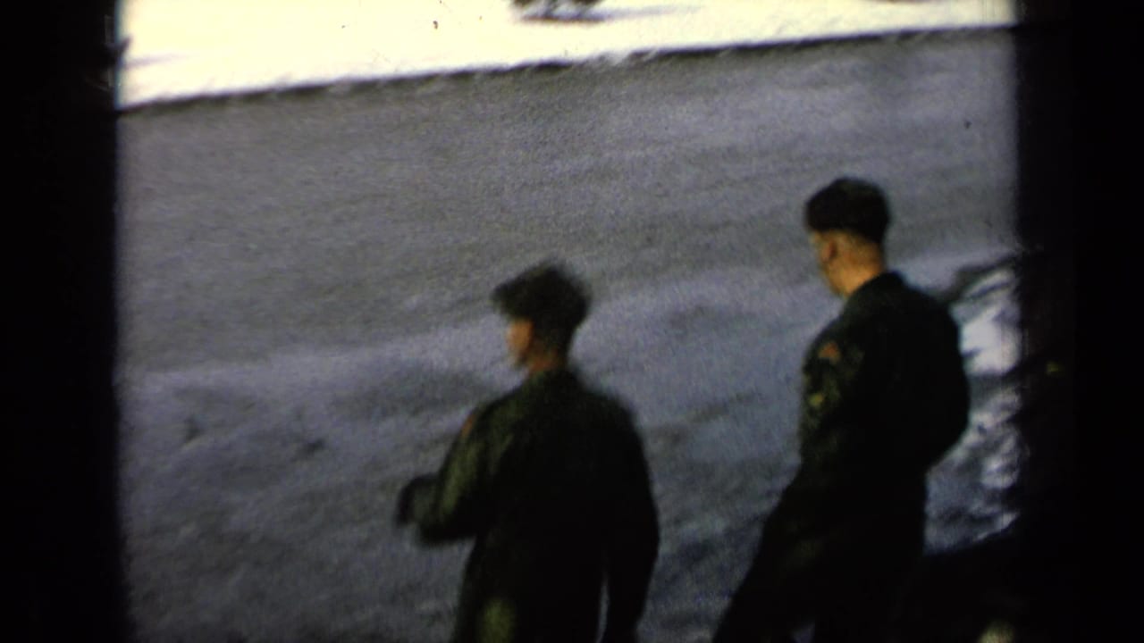 Two uniformed soldiers seen from above near snowy steps and a paved road.