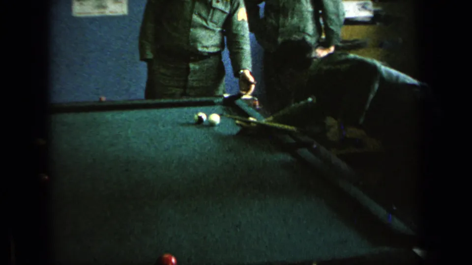 1963 8mm frame of uniformed men near a green pool table inside a Germany military base recreation room.