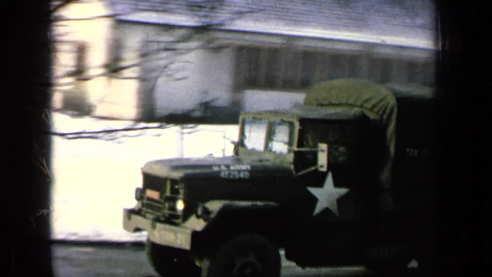 A close passing view shows the green Army truck, white star marking, canvas cover, and snowy base building.